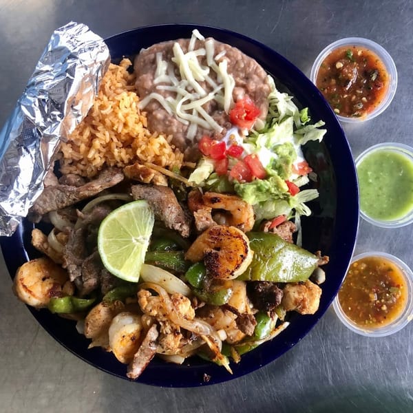 Uncle Berto's Burritos fajita plate with shrimp, steak, rice, beans, salad, and three salsas.