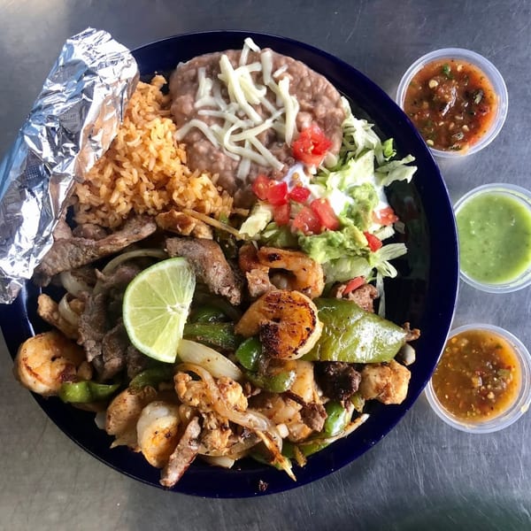Uncle Berto's Burritos fajita plate with shrimp, steak, rice, beans, salad, and three salsas.