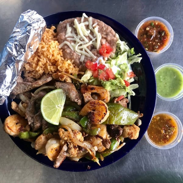 Uncle Berto's Burritos fajita plate with shrimp, steak, rice, beans, guacamole, and salsa.